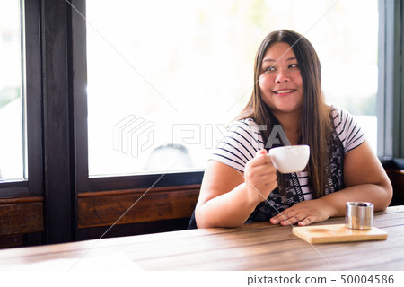 Beautiful overweight Asian woman relaxing at the coffee shop Beautiful overweight Asian woman relaxing at the coffee shop 50004586