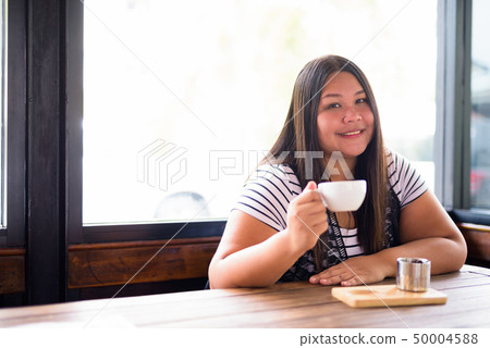 Beautiful overweight Asian woman relaxing at the coffee shop Beautiful overweight Asian woman relaxing at the coffee shop 50004588