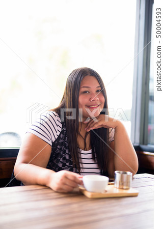 Beautiful overweight Asian woman relaxing at the coffee shop Beautiful overweight Asian woman relaxing at the coffee shop 50004593