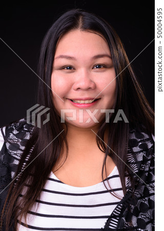 Beautiful overweight Asian woman against black background Beautiful overweight Asian woman against black background 50004595