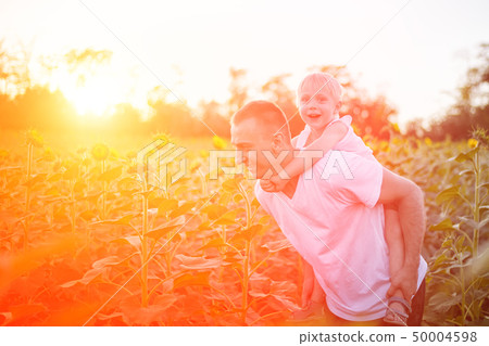 Happy father with son on back walking on a green Happy father with son on back walking on a green 50004598