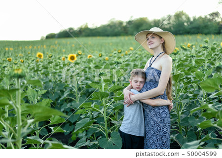 Sad small son embraces pregnant mother standing on Sad small son embraces pregnant mother standing on 50004599