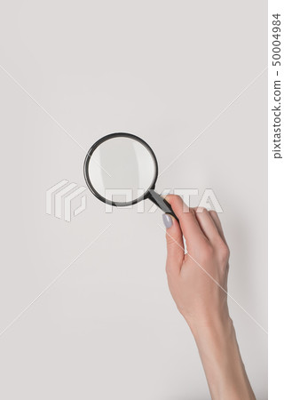 Female hand holding magnifier isolate on light 50004984