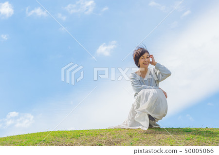 Under the blue sky Refreshing alafour woman on the grass hill 50005066