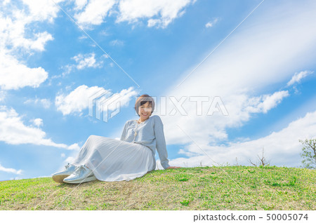 Under the blue sky Refreshing alafour woman on the grass hill 50005074