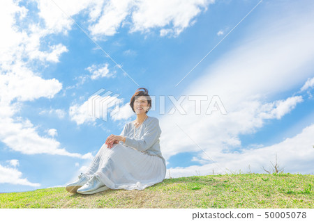 Under the blue sky Refreshing alafour woman on the grass hill 50005078