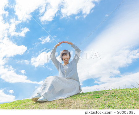 Under the blue sky Refreshing alafour woman on the grass hill 50005083