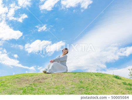 Under the blue sky Refreshing alafour woman on the grass hill 50005084