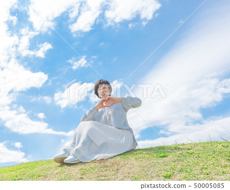 Under the blue sky Refreshing alafour woman on the grass hill 50005085