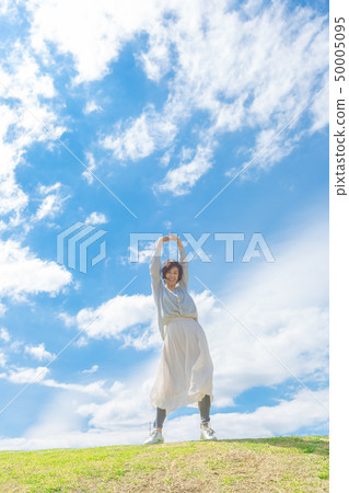 Under the blue sky Refreshing alafour woman on the grass hill 50005095