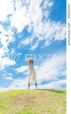Under the blue sky Refreshing alafour woman on the grass hill 50005097
