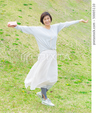 刷新的Ala拿著在草的四名婦女一本書在藍天下 50005110