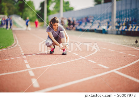 Theme sports and sportswear. A young Caucasian woman in uniform lacing shoelaces adjusting shoes 50007978