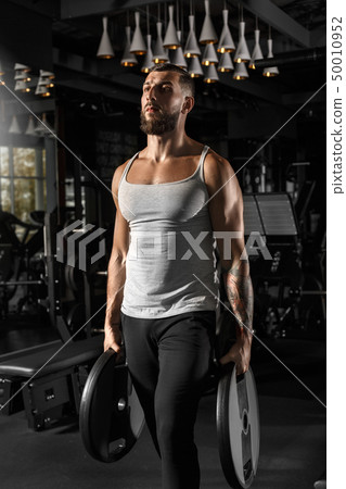 Bodybuilding. Bearded man standing at gym with weight plates confident 50010952