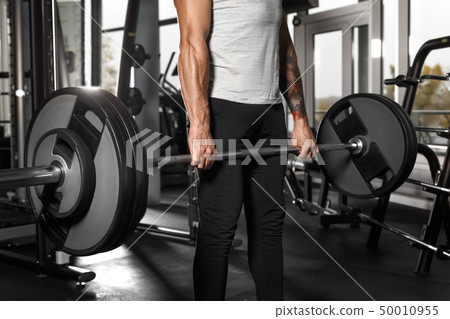 Bodybuilding. Man standing at gym with barbell preparing to lift close-up 50010955
