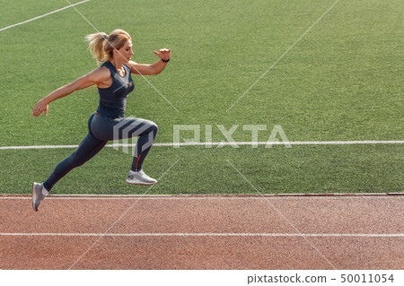 Sporty Lifestyle. Young woman on stadium running concentrated side view Sporty Lifestyle. Young woman on stadium running concentrated side view 50011054