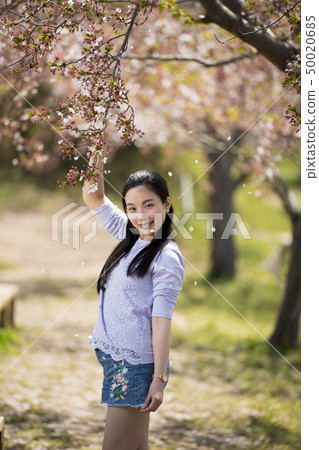 A smiling young woman under the leaf cherry blossoms of Fujiwara Palace in Kashihara City, Nara Prefecture 50020685