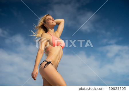 Blong young girl wearing swimming suit on the sky background. Summer day and happy holiday concept. Blong young girl wearing swimming suit on the sky background. Summer day and happy holiday concept. 50023505