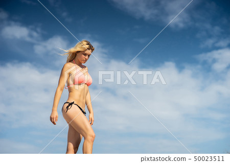 Blong young girl wearing swimming suit on the sky background. Summer day and happy holiday concept. 50023511