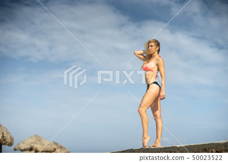 Beautiful young girl wearing swimming suit on the sky background. Summer day and happy holiday 50023522