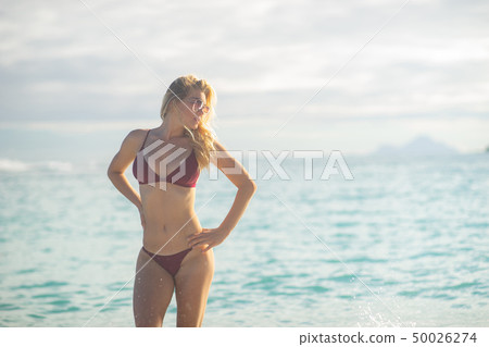 Attractive blonde girl walking on the beach, fit sporty healthy sexy body in bikini, woman enjoys 50026274