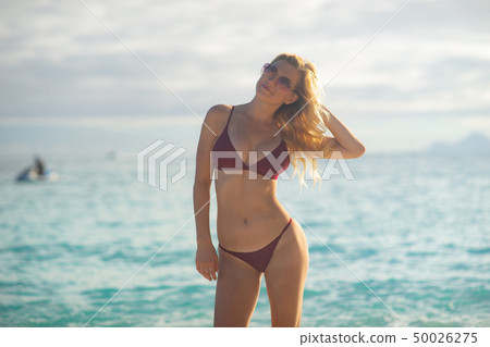 Attractive blonde girl walking on the beach, fit sporty healthy sexy body in bikini, woman enjoys Attractive blonde girl walking on the beach, fit sporty healthy sexy body in bikini, woman enjoys 50026275
