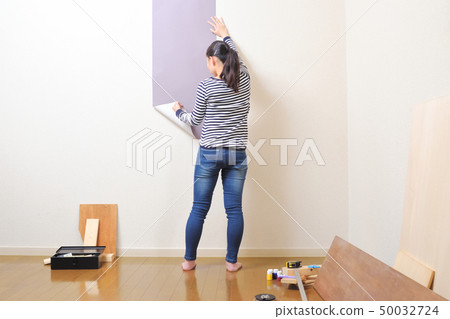 DIY woman putting a wallpaper 50032724