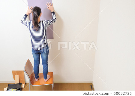 DIY woman putting a wallpaper 50032725