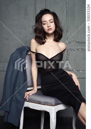 Woman in evening dress sitting on chair 50033104