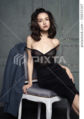 Woman in evening dress sitting on chair Woman in evening dress sitting on chair 50033107