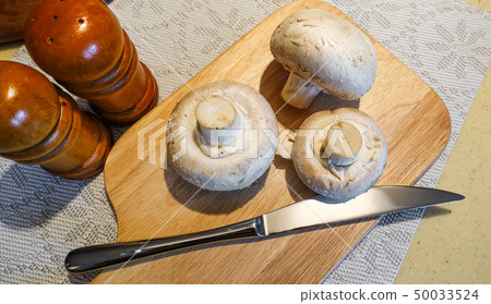 Fresh champignon mushrooms on a cutting board. 50033524