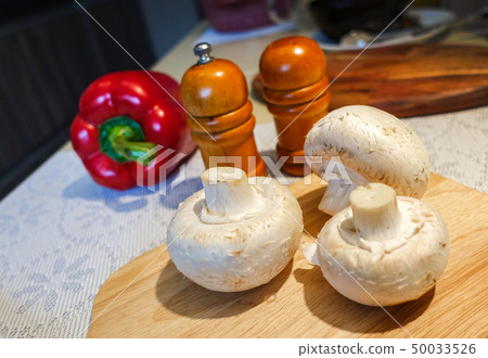 Fresh champignon mushrooms on a cutting board. Fresh champignon mushrooms on a cutting board. 50033526
