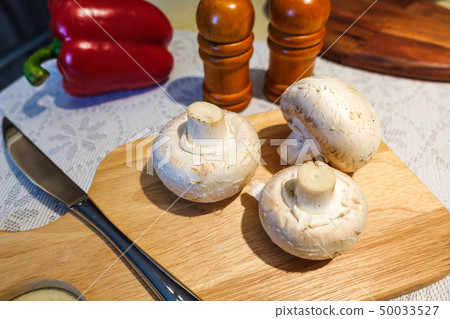 Fresh champignon mushrooms on a cutting board. 50033527
