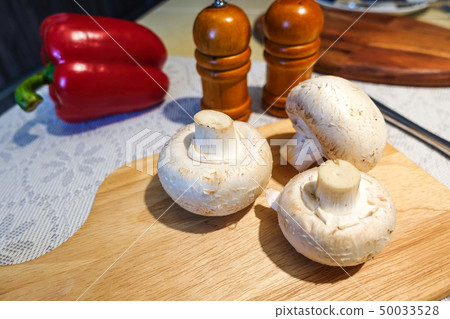 Fresh champignon mushrooms on a cutting board. 50033528