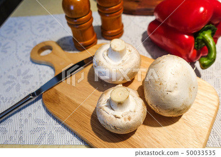 Fresh champignon mushrooms on a cutting board. 50033535