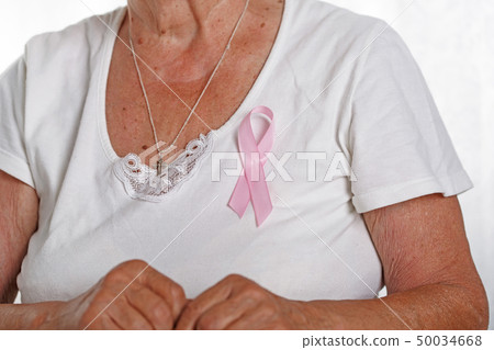 Chest of elder woman with pinned pink breast cancer awareness ribbon Chest of elder woman with pinned pink breast cancer awareness ribbon 50034668