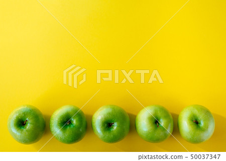 Group of green apples on yellow background Group of green apples on yellow background 50037347