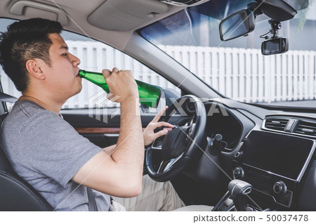 Young asian man drives a car with drunk a bottle 50037478