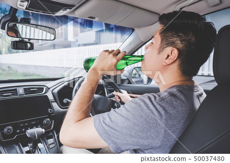 Young asian man drives a car with drunk a bottle 50037480