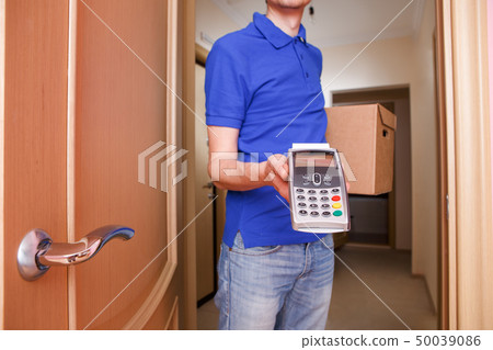 Courier man in blue t-shirt and baseball cap with pin pad and cardboard boxes in hands. 50039086
