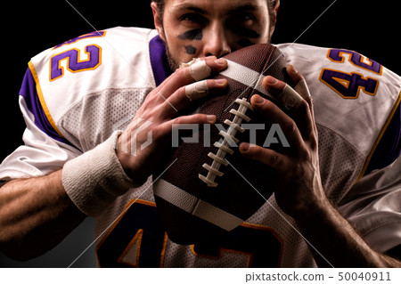 Close up portrait of American Football Player who gently kiss the ball 50040911