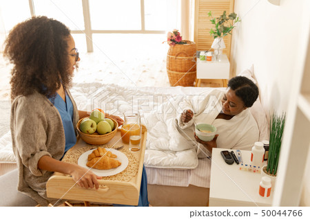 Caring curly nurse bringing tray with breakfast for patient Caring curly nurse bringing tray with breakfast for patient 50044766