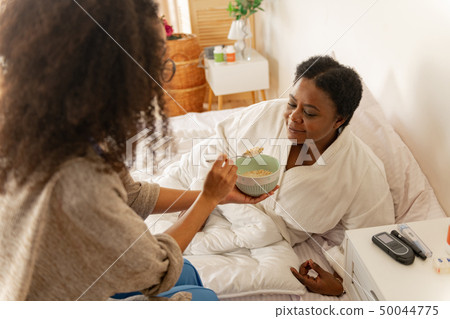 Nurse giving some porridge for woman lying in bed after surgery Nurse giving some porridge for woman lying in bed after surgery 50044775