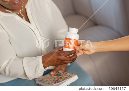 Aged patient of nursing house taking supplements from nurse 50045157