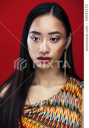 young pretty asian girl with makeup posing on red background, lifestyle diverse rases people concept 50045272