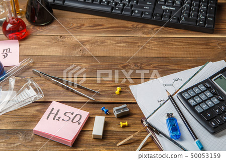 Chemical flasks, tweezers, keyboard, notebooks on a wooden table with copyspase. 50053159