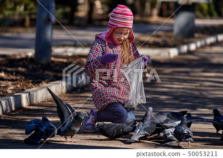 A girl child in a red jacket, hat and glasses 50053211