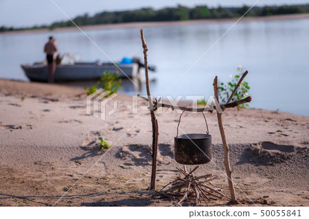 dinner in nature old pot hanging on a wooden stick dinner in nature old pot hanging on a wooden stick 50055841