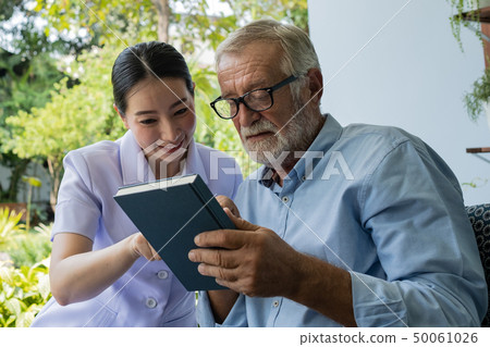 senior man happiness with smiling nurse, read book senior man happiness with smiling nurse, read book 50061026