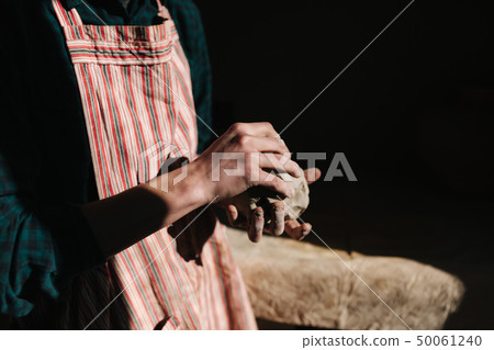 Close up of man works with clay. Male potter kneads and moistens the clay before work, toned 50061240